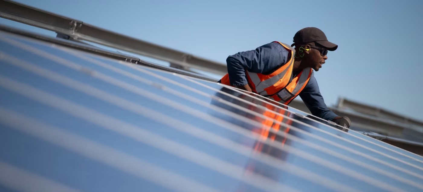 A worker fits solar panels onto frames during construction at South Africa's first municipally owned solar plant, on June 05, 2025, in Atlantis, about 40km from Cape Town