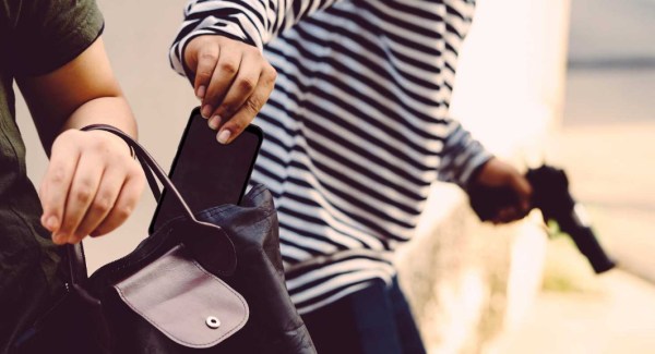 Generic image of a man stealing phone from somebody else' purse