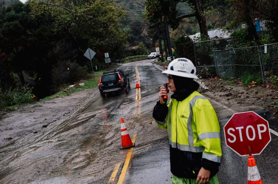 A crew member directs traffic around a flooded road in Malibu, Calif., on Saturday, Nov. 15, 2025, as part of the state got hit with heavy rains. Some residents of Southern California were under evacuation orders on Saturday as an unusually strong storm system moved through the region, bringing with it a risk for flash flooding and landslides in areas recently burned by wildfires.